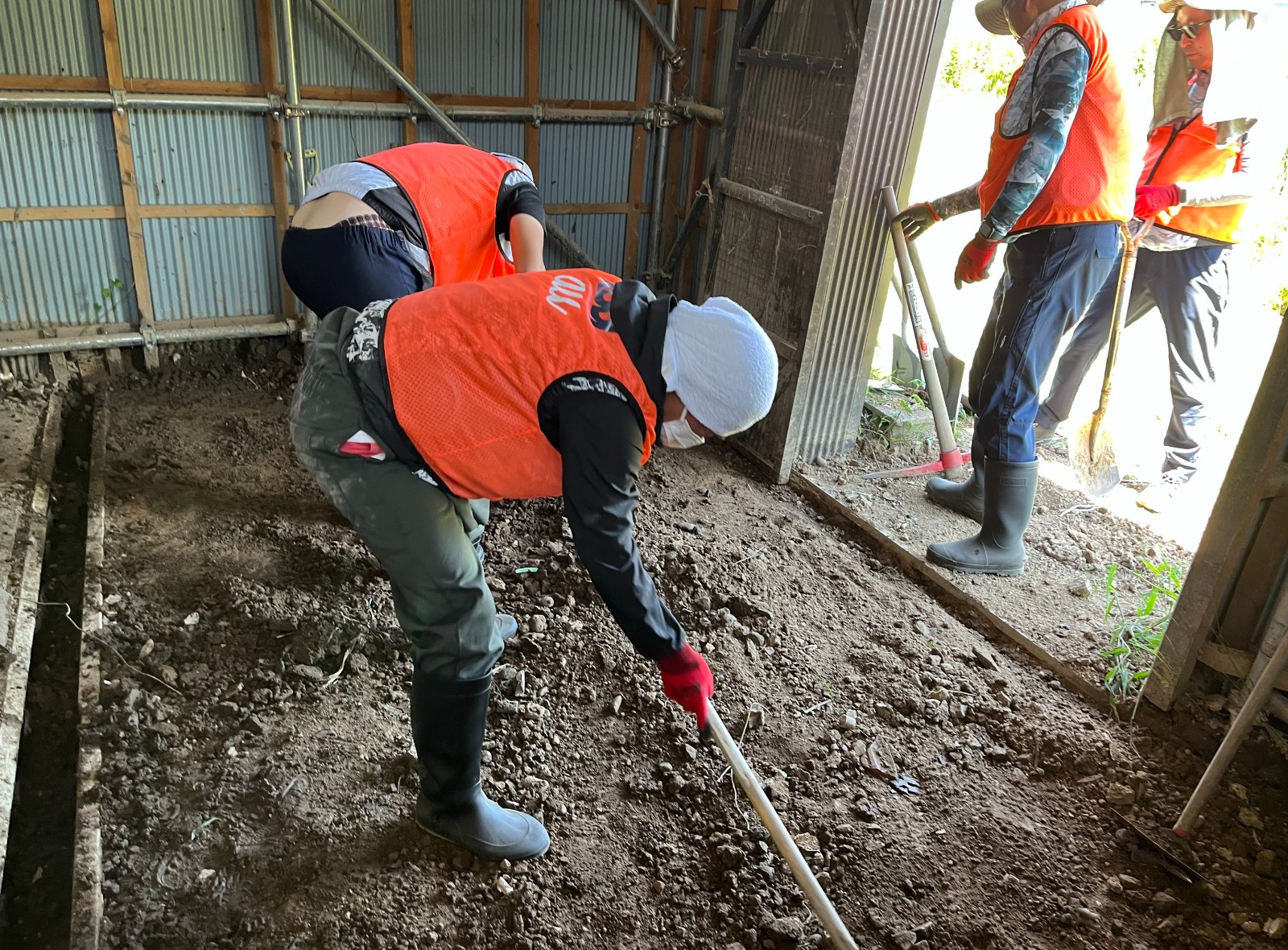 納屋に流入した泥をかき出す様子の写真