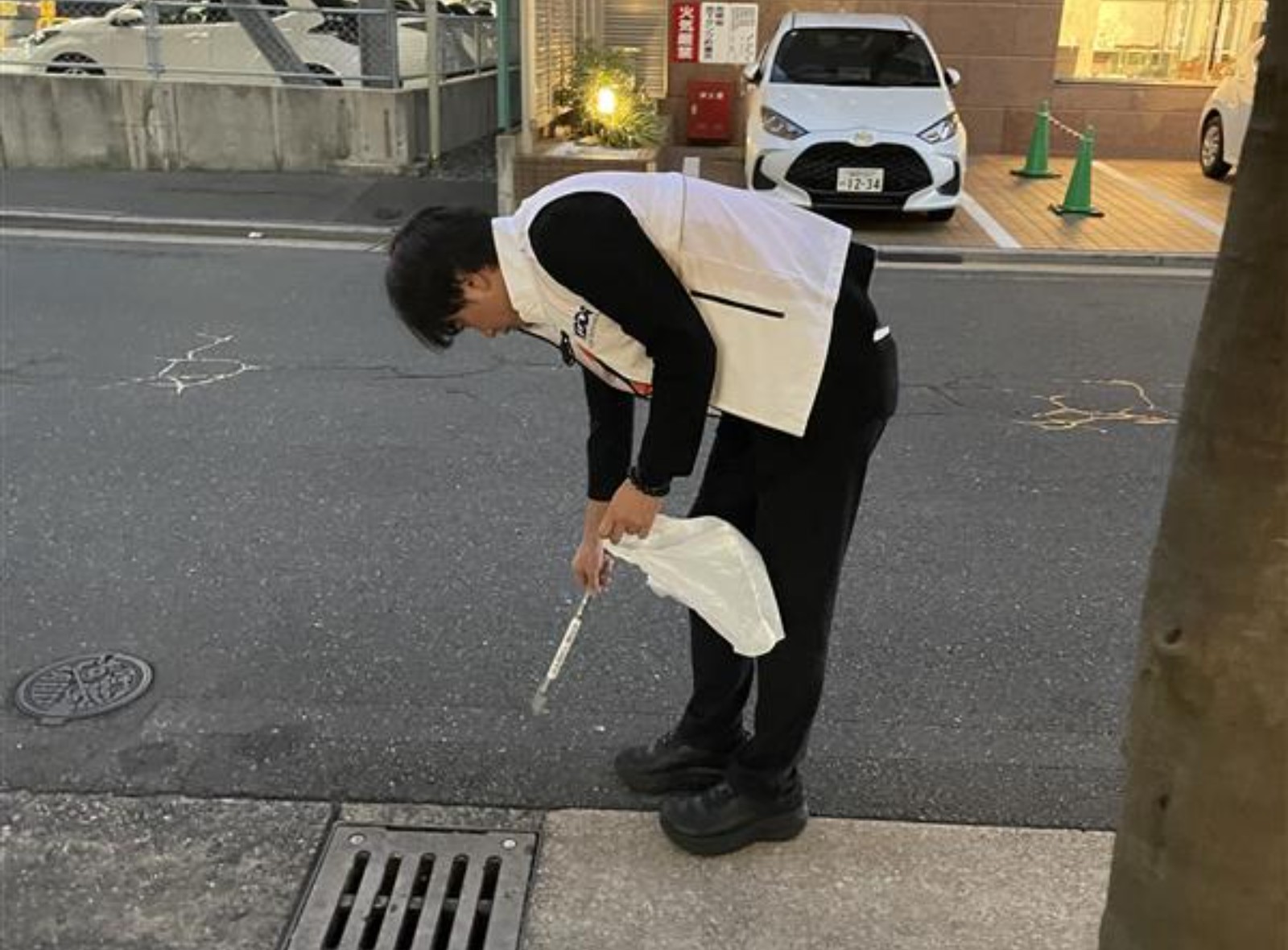 排水溝近くでゴミを回収する様子の写真