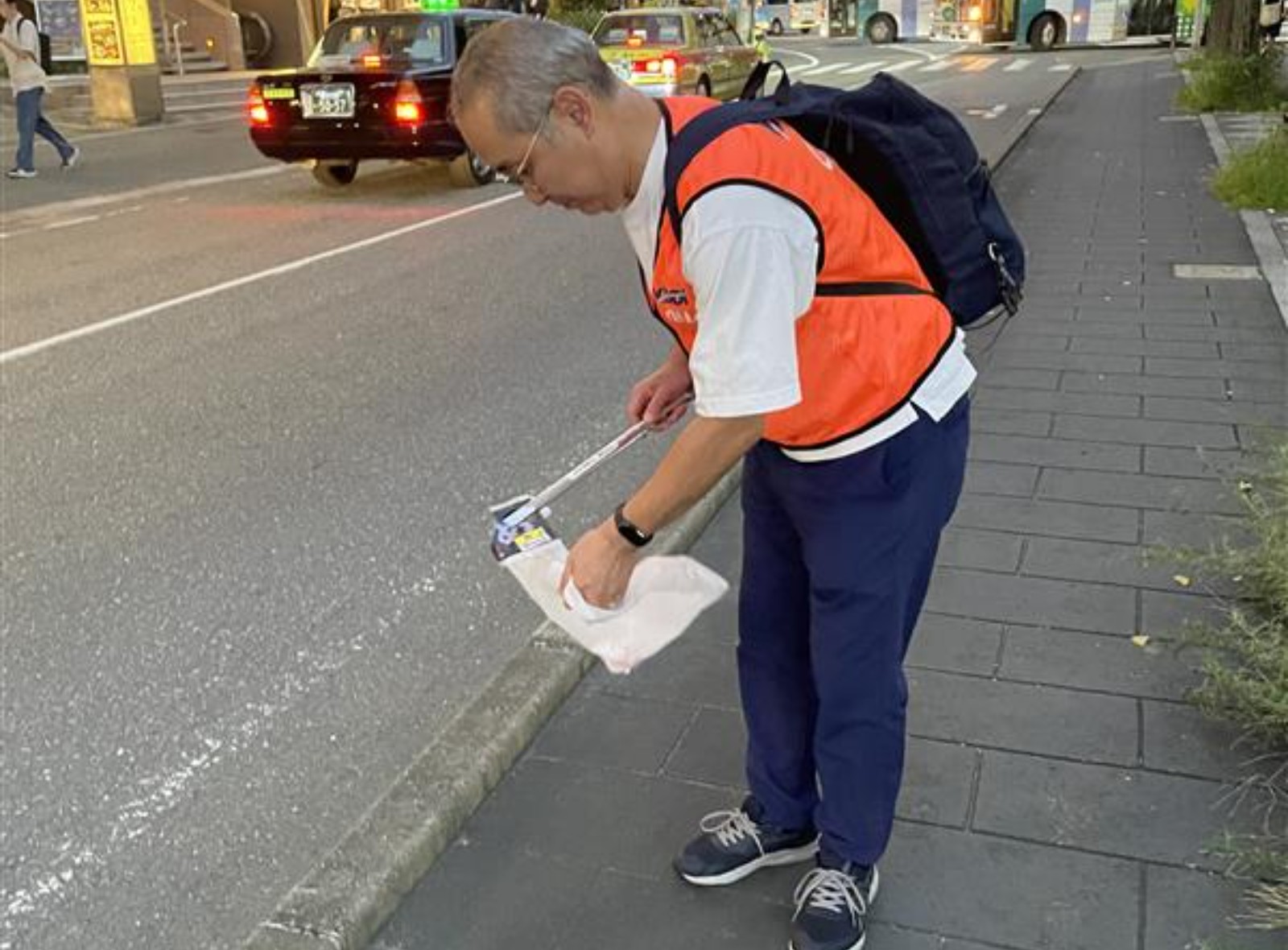 歩道でゴミを回収する様子の写真