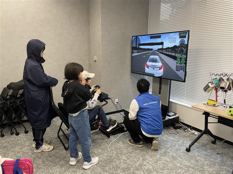 ドライビングシミュレータを家族で楽しむ様子の写真